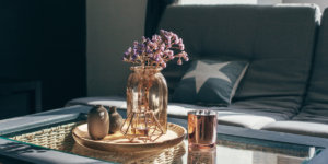 A glass jar with purple flowers sitting on a coffee table